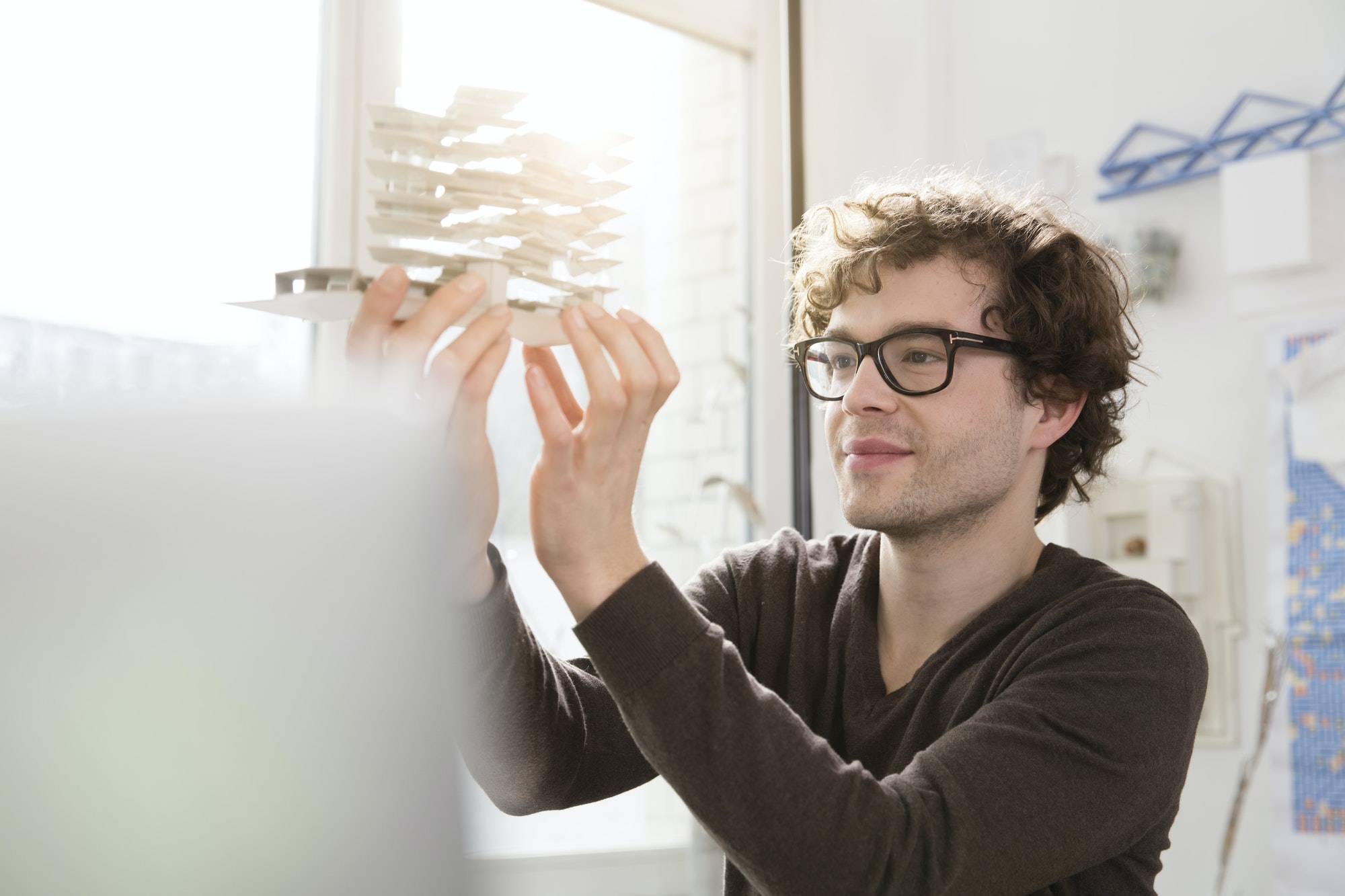 Portrait of young architect looking at architectural model