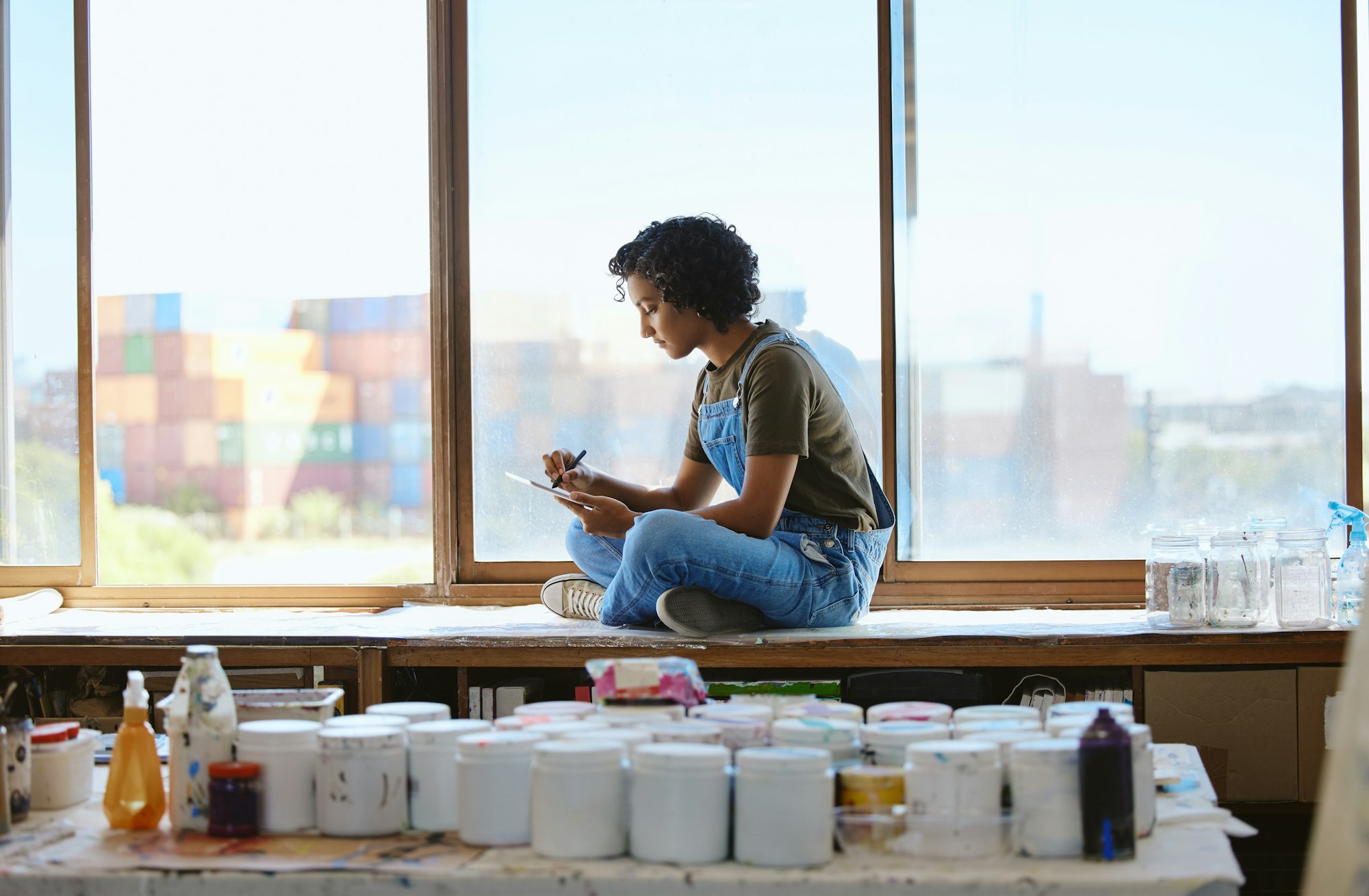 Tablet, creative and woman drawing on a mobile app for painting inspiration at a window in a studio